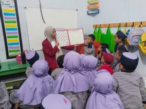 mahasiswa PG PAUD UMSIDA, Silvia Andini, menggunakan Alat Permainan Edukatif (APE) Lingoo Book untuk mengenalkan huruf vokal kepada anak Kelompok Bermain